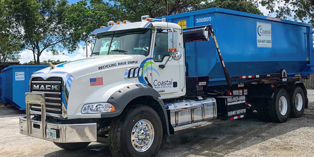 Truck carrying dumpster in Coastal Waste's Yard in Pompano Beach, FL